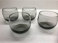 Set of 4 chubby smokey grey scotch glasses shown from front angle on white background.