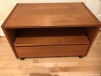 Front view of mid-century modern teak entertainment table on rollers with closed compartments.