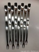 Photo showing all eight lobster/crab forks laid out side by side, displaying the polished stainless steel finish, indented grip area, and fork ends.