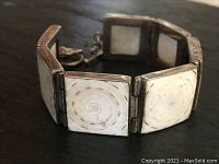 Front view of the sterling silver bracelet showing square fossilized shell panels polished and bezel-set with visible markings on the silver frame.
