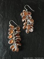 Front and side view of both earrings showing the cascading arrangement of bezel-set tangerine oval gemstones in sterling silver.