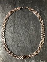 Full view of necklace laid flat on dark surface