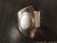 Close-up view of sterling silver wrapped ring with central oval moonstone set on textured dark background.