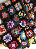 Close-up of multi-coloured crochet squares with black edging highlighting the detail and colors.
