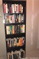 Photo of entire bookshelf unit showing four full shelves and part of the bottom shelf, all filled with books.