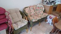 The chair and love seat set positioned near a wall with kitchen area adjacent, showing the overall condition and setup.