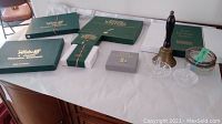 Overview of the lot items displayed on a table including placemat boxes, coasters, bell, and glass items