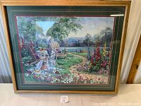 Framed Barbara Mock print showing full artwork with garden chairs, table, lake, and floral path.