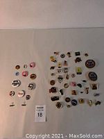 Wide view of entire pin and button lot arranged on a light surface with all items visible