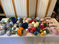 Overall spread of yarn collection showing many skeins and balls in a variety of colors on a table.