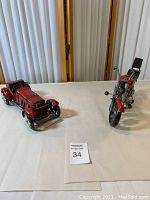 Overview of the red metal vintage car and motorcycle models on display on a white surface