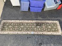 Full view of the rectangular runner rug laid out on asphalt showing overall design and size.