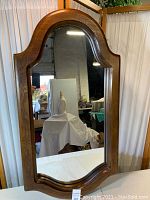 Full view of the solid wood framed arched top mirror showing natural wood grain and room reflection.