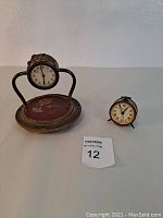 Lot showing both vintage ornate brass clocks: larger clock with floral base and smaller Bradley clock