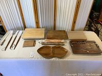 Full view of wood cutting boards, snack tray, fish board, cheese board with knife, and grill utensils arranged on table.