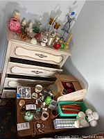Overview showing various candles, candle holders, figurines, and decor items arranged on a dresser and a folded table.