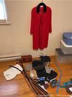 Full view of the lot on the floor with the red London Fog jacket hanging on the wall. Shows jackets, handbags, belts, gloves, wallet and sweater vest.