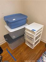 Four stacked plastic storage bins with lids on left; one white four-drawer plastic storage box on right.