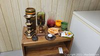 Photo of ceramic, glass vases, candle holders, and decorative bowls arranged on a wooden shelf and table.