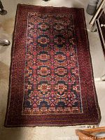 Full view of antique Middle Eastern area rug showing overall pattern and colors.
