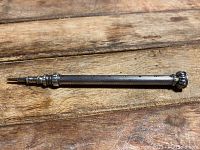 Full view of antique silver mechanical pencil showing textured silver barrel and tip.