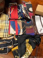 Top view of six scarves arranged on wooden surface showing full patterns and colors