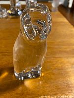 Frontal view of clear crystal owl figurine on wooden surface
