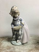 Front view of porcelain Lladro figurine showing harlequin costume with accordion