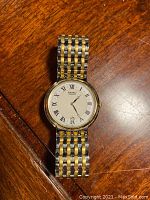 Front view of men's Seiko watch showing white dial with Roman numerals and two-tone metal bracelet.