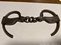 Top-down view of both cuffs and connecting chain on white background showing overall shape and condition