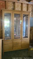 Front view of the Ethan Allen lighted china cabinet with three glass doors and six drawers.