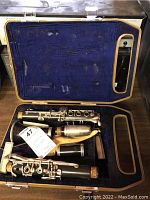 Disassembled clarinet in soft-lined protective case showing four parts of the clarinet and small accessories.