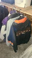 Four jackets and one sweater hanging showing logos of Colorado Rockies and Denver Broncos, with different color schemes and materials.
