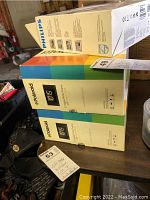 Three boxed digital photo frames stacked on a table: two Polaroid brand and one Philips brand, showing packaging colors and branding.
