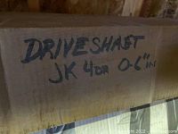 Cardboard box with handwritten label 'DRIVESHAFT JK 4DR 0-6 IN' indicating driveshaft for Jeep JK 4-door vehicle, approximately 0-6 inches.