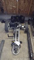 Folded Bat Caddy electric golf caddy on concrete floor showing frame, wheels and motor housing