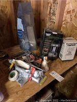 Wide view of the lot showing lantern, phone holder, hardware packs, tape rolls, and ceramic cat figurine