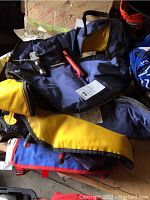 First image showing stacked blue and yellow life preservers with visible straps and attached red whistle