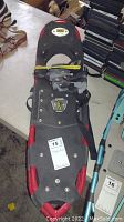 Full view of one Atlas snowshoe showing black and red frame, bindings, and marked with lot tag.