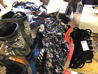 Adult size 9 dirt bike boots next to dirt bike clothing on a surface