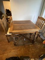 Barley twist oak refectory table with two solid wood chairs, table shown with leaves closed.