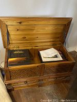 Open blanket box showing stored items inside and carved wood panels.