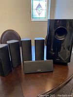 Front view of five Onkyo satellite speakers and one large subwoofer on a wooden table