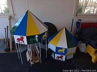 Photo showing fully assembled colorful carousel with metal poles and horse silhouette cut-outs next to a partially assembled carousel component