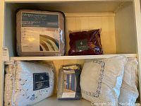 Lot overview on shelf showing comforter, bed skirt, pillows, window panels and bedspread