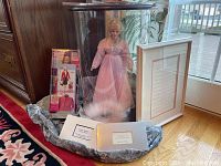 Mary Kay consultant Barbie doll in display case, Barbie consultant outfit box, framed document, and part of other material visible