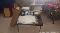 View of all items laid out on table including boxed TCP LED light bulbs, toilet seat in package, faucet box, and various other boxes.