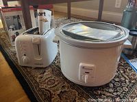 Cuisinart CPT-120 toaster and Toastmaster model 1315 slow cooker shown on carpet with packaging visible in background