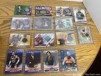 Top-down image showing the full set of 15 WWE numbered and rare cards with patches and memorabilia in plastic cases.