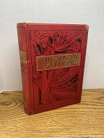 Front cover of the 1896 The Sunday At Home book showing ornate design in black and gold on red background.